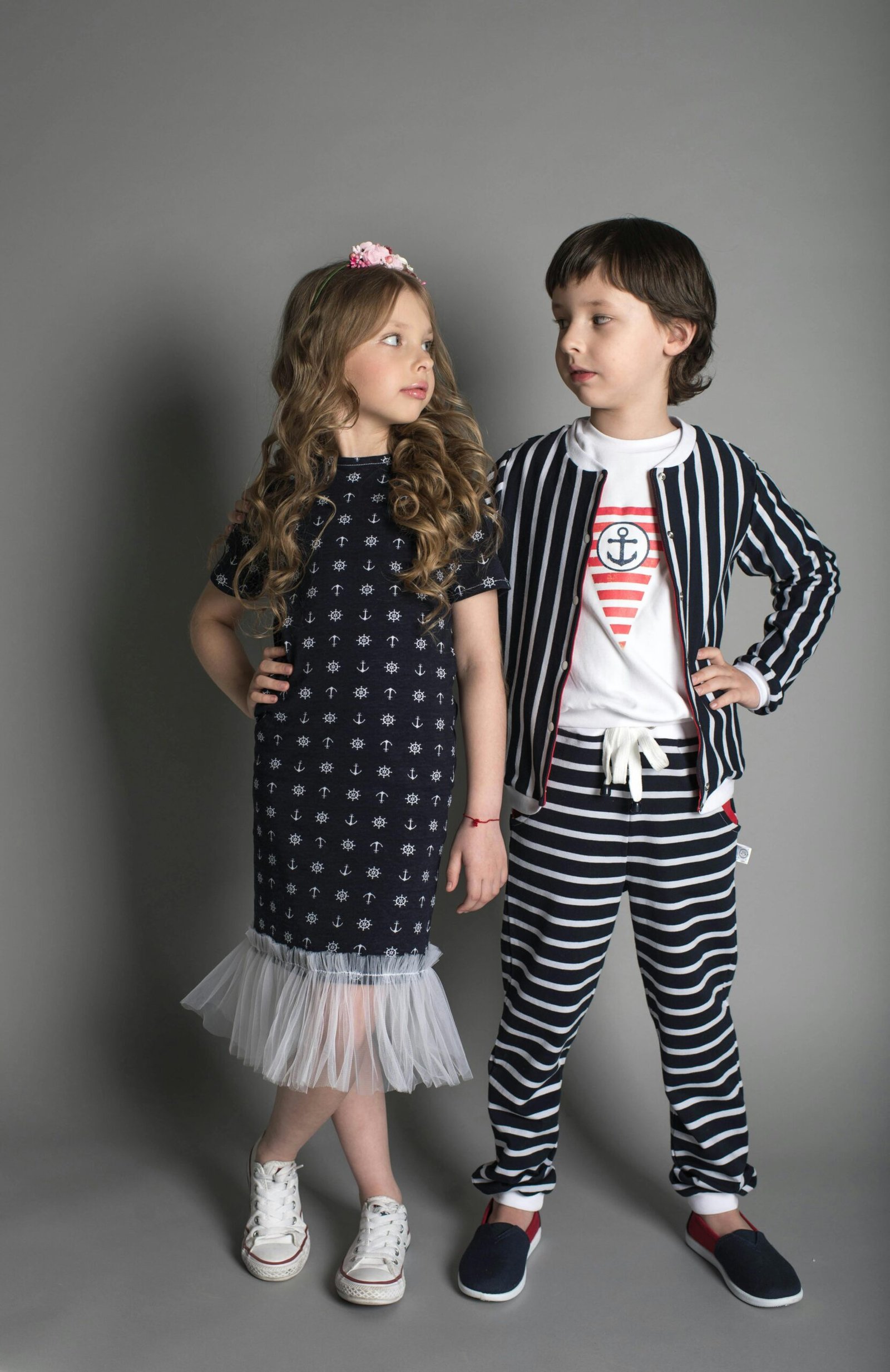 Two children in stylish nautical-themed clothing posing confidently in a studio.